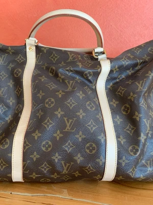  Keepall  väska - Säljer en klassisk Keepall resväska i brunt monogramcanvas med beigea handtag och detaljer. Väskan har guldiga metalldetaljer och ett hänglås med -logga. Perfekt för weekendresor och har en tidlös design. Tyvärr har jag förlagt nyckeln