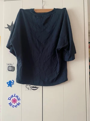 Mörkblå loose topp med trekvartsärm - En enkel och stilren mörkblå topp med loose passform och trekvartsärmar. Perfekt till jeans eller kjol för en avslappnad look. Tillverkad i mjuk bomull som känns skön mot huden.