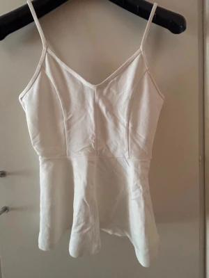 Vit  linnetopp med v-ringning - Säljer en stilren vit linnetopp med smala axelband och v-ringad hals från Gina Tricot. Endast använd ett fåtal gånger. Passar perfekt nu till varmare dagar🌸