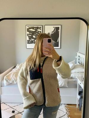 Beige teddyväst  - Säljer en helt ny beige teddyväst med svarta detaljer och röda dragkedjor. Alla fickor har dragkedja 🤍
