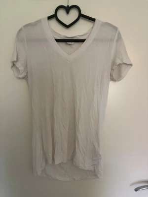 Vit v-ringad t-shirt - En enkel vit t-shirt med v-ringning och korta ärmar. T-shirten har en avslappnad passform och är tillverkad i mjuk bomull, perfekt för en clean och basic look. Xs men passar till s också