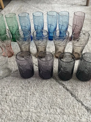 Flerfärgade Coca-Cola glas - Säljer ett set med färgglada Coca-Cola glas i olika nyanser som grön, blå, lila, rosa och klar. Glasen har den klassiska Coca-Cola-loggan i relief och finns i olika former och storlekar. Perfekt för dig som vill ha en unik samling till köket.
