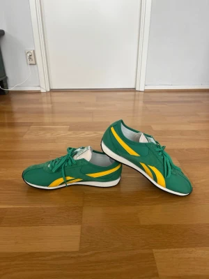 Reebok sneakers mycket gott skick – Storlek 45 - Säljer ett par snygga Reebok-sneakers i storlek 45. Skorna är i mycket gott skick och har använts extremt lite vilket syns på det fina helhetsintrycket. Den gröna färgen med gula detaljer ger en klassisk retrokänsla som sticker ut på ett stilrent sätt. Skorna är lätta, bekväma och passar lika bra till vardags som till en mer sportig look. Ett perfekt val för dig som gillar både komfort och tidlös design.