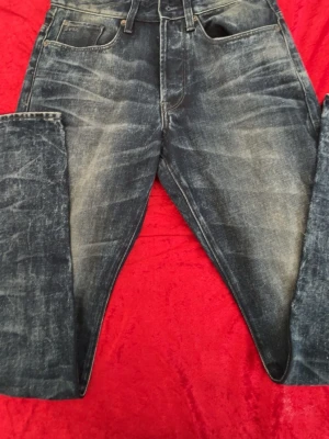 G star raw jeans - Säljer ett par mörkblå jeans med snyggt tvättad och sliten look. Jeansen har klassisk femficksmodell, raka ben och normal midja. Materialet är denim i bomull. Perfekta för en avslappnad och trendig stil.   W28 L32
