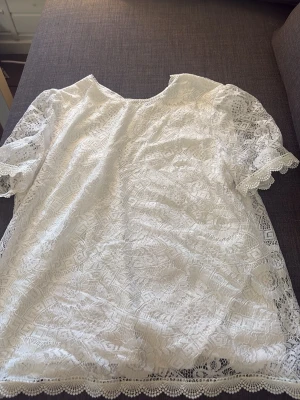 Vit spetsblus med korta ärmar - Söt vit blus i spets med korta ärmar och rund halsringning. Blusen har ett fint spets matrial.Varan är i fint skick!
