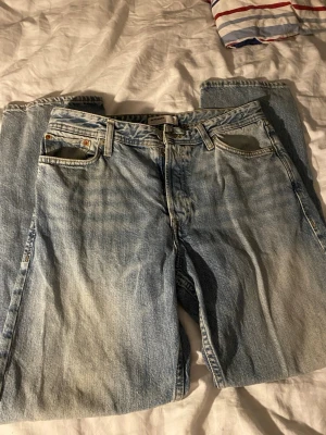 Levi's 501 ljusblå jeans - Klassiska Levi's 501 jeans i ljusblå tvätt med raka ben och femficksmodell. Jeansen har knappgylf och den ikoniska läderpatchen bak i midjan. Tillverkade i slitstark bomullsdenim, perfekt för en avslappnad och tidlös look.