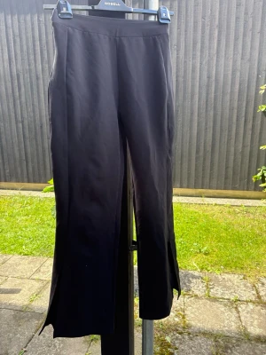 Svarta kostymbyxor med slits oanvända  - Säljer ett par svarta kostymbyxor med trendiga slitsar nertill på benen. De har hög midja och är i stretchigt material som sitter snyggt. Perfekta till sneakers eller boots för en cool look.