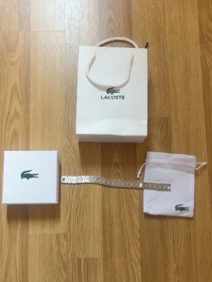 Silverfärgad klocka från Lacoste - Stilren klocka från Lacoste i silverfärg med metallarmband. Kommer med originalförpackning, tygpåse och presentpåse med Lacoste-logga. Perfekt accessoar för dig som gillar klassisk och enkel design.