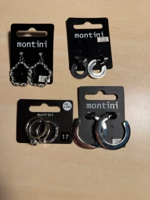 Fyra par silvriga smycken Montini - Säljer tre par örhängen och ringar från Montini (ur&pen) i  olika former. Två par är hoops med slät yta, ett par har en twistad design och ett par är dekorerade med små pärlor. Alla är i silverfärgad metall och passar perfekt för dig som gillar att mixa och matcha olika stilar.