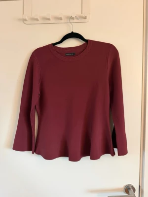 Mörkröd tröja från Stockh LM - Säljer en mörkröd långärmad tröja från Stockh LM. Tröjan har rund halsringning, lätt utsvängda ärmar och en mjuk, stretchig kvalitet. Passformen är något figurnära upptill och lösare nedtill för en snygg siluett. Sparsamt använd.
