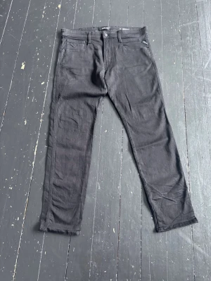 Svarta slim fit jeans från Replay  - Svarta jeans från Lee i slim fit-modell med klassisk femficksdesign och dragkedjegylf. Jeansen har raka ben och är tillverkade i ett stretchigt denimtyg för extra komfort. Perfekta för en stilren och avslappnad look.