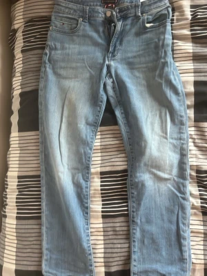 Ljusblå raka jeans - Säljer ett par ljusblå jeans med raka ben och klassisk femficksdesign. Jeansen har en lätt tvättad look och normalhög midja. Perfekta för en avslappnad stil och passar till det mesta. Materialet är denim i bomull.
