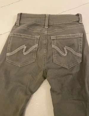 Olivgröna jeans från Nelly - Low waist bootcut stitch jeans från Nelly i storlek 32. Olivgröna. Jättefina och i mycket bra skick, har sytt upp de lite, så innerbenslängd 70 cm💓