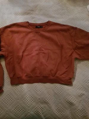 Röd croppad sweatshirt från Bik Bok - Säljer en röd croppad sweatshirt från Bik Bok. Tröjan har rund halsringning, långa ärmar och ribbade muddar vid ärmslut och nederkant. Materialet är mjukt och skönt mot huden.