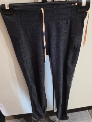 Svarta träningsbyxor från H&M Sport - Snygga svarta träningsbyxor från H&M Sport med dragsko i midjan och praktisk ficka med dragkedja på sidan. Tillverkade i ett stretchigt och mjukt material som passar perfekt för träning eller löpning.