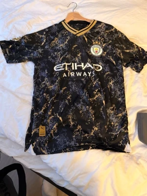 Manchester City bortatröja Puma - Snygg Manchester City bortatröja från Puma i svart med guld- och grått mönster. Slå ett PM för mer bilder, pris går att diskutera