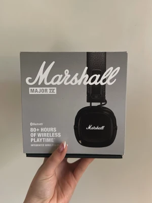 Marshall Major IV trådlösa hörlurar - Snygga svarta Marshall Major IV over-ear hörlurar med klassisk retrodesign. Trådlösa via Bluetooth och ger över 80 timmars batteritid. Mjuka öronkuddar och vadderat huvudband i konstläder för extra komfort. Perfekta för musik och gaming.