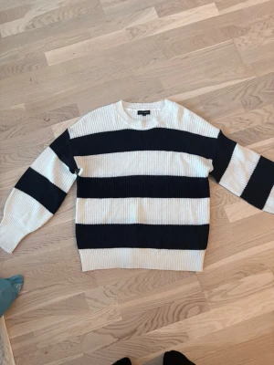 Randig stickad tröja från Only - Snygg stickad tröja från Only med breda svarta och vita ränder. Tröjan har rund halsringning och ribbstickade muddar vid ärmslut och nederkant. Perfekt för en chill och trendig look.