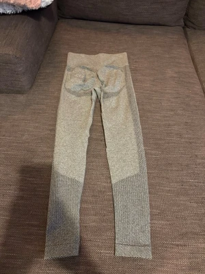 Grå sömlösa leggings med mönster - Snygga grå leggings med hög midja och sömlös design. De har diskret mönster längs benen och förstärkning vid rumpan för extra passform. Perfekta för träning eller chill. Materialet är stretchigt och följsamt.