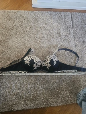Svart spets-bh från Intimissimi  - Snygg svart bh med vadderade kupor och snygg vit spetsbrodyr framtill. !!Den är insydd så den är 67ish runt istället för 75-80!! men har samma kupa som en 80B men passar som en 75C/70D så mät gärna innan 