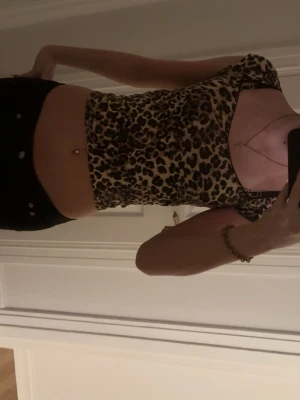 Leopardmönstrad croppad topp - Snygg croppad topp med leopardmönster och korta ärmar. Toppens material är stretchigt och sitter tight mot kroppen, perfekt för en trendig look. Rundad halsringning och figurnära passform.
