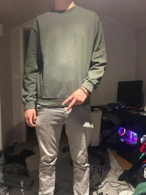 Ljus grön sweatshirt i basic stil - Enkel och stilren olivgrön sweatshirt med rund hals och ribbade muddar. Tröjan har en avslappnad passform och är perfekt för en casual look. Passar bra till jeans eller mjukisbyxor. Aldrig använd