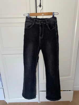 Jeans - Ett fina par svarta utsängda jeans med design på bakfickorna. Lite slitna i ändarna men syns inte så mycket när man har på sig dom.