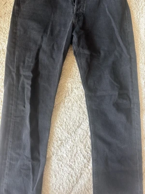 Svarta jeans från Jack & Jones - Säljer ett par svarta jeans från Jack & Jones med klassisk rak passform. Jeansen har knappgylf och tydliga sömmar längs benen. Perfekta för dig som gillar en stilren och enkel look. W 30, L 32. Pris kan diskuteras privat.