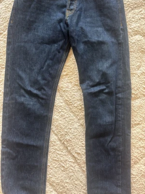 Mörkblå jeans från Jack & Jones - Snygga mörkblå jeans från Jack & Jones med klassisk femficksmodell och synliga kontrastsömmar. Jeansen har knappgylf och är tillverkade i slitstark denim. Perfekta för en avslappnad och trendig look. Använt dom en gång. W 31, L 32. Pris kan diskuteras privat. 