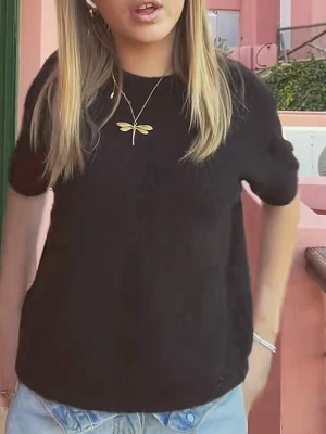 Svart stickad kortärmad topp - En svart stickad topp med korta ärmar och rund hals. Perfekt för att skapa en enkel och stilren look. Materialet är mjukt och ger en skön känsla mot huden. Passformen är normal och toppen är lätt att matcha med jeans eller kjol.