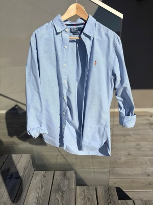 Ljusblå skjorta från Polo Ralph Lauren - Klassisk ljusblå skjorta från Polo Ralph Lauren. Passar perfekt nu inför sommaren. Skulle säga att den passar om man är rutn 185 