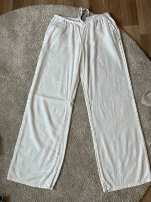 Vita linnebyxor  - Säljer ett par vita linnebyxor med vanliga fickor fram. Byxorna har raka, vida ben och är tillverkade i ett lätt och luftigt linnematerial. Perfekta för en chill och stilren look. 