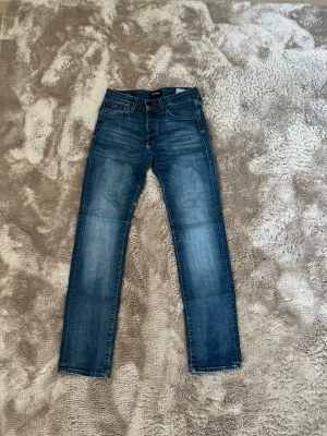 Jack and Jones jeans   - Säljer ett par klassiska blå jeans med raka ben och snygga tvättade detaljer framtill och baktill. Jeansen har fem fickor, bälteshällor och knappgylf. Perfekta till vardagslooken och passar bra