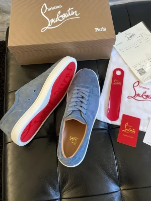 Blåa Christian Louboutin sneakers - Snygga blåa sneakers från Christian Louboutin i mocka med klassisk röd sula. Skorna har vita kanter, rund tå och matchande blå skosnören. Insidan är ljusbrun och märket syns både på insidan och på sulan. Perfekta för dig som gillar exklusiva detaljer. Helt nya aldrig använda 10/10 skick. Storlek 43. Pris kan diskuteras vid snabb affär 