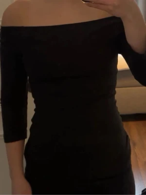 Svart offshoulder top Even&Odd - Säljer en svart offshoulder top från Even&Odd. Toppen har en tight passform och trekvartsärm, vilket ger en stilren och modern look. Perfekt för dig som vill ha något enkelt men snyggt.