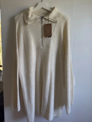 Vit stickad tröja med dragkedja Vero Moda - Säljer en krämvit stickad tröja från Vero Moda med hög krage och dragkedja framtill. Tröjan har avslappnad passform, långa ärmar och är tillverkad i mjukt material. 