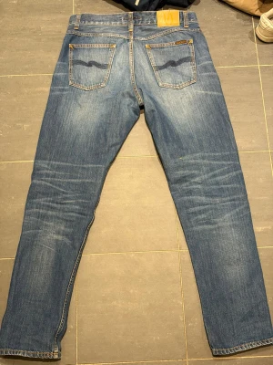 Nudie jeans  - Ett par nudie jeans som är i modellen steady Eddie 2 med en rak passform. Jeansen är l34 och w32. Jeansen har en riktig snygg och slitning därtill som gör dom riktigt coola. Ytterbenslängd: 108 cm midjemått: 44,5cm och benöppning: 18cm