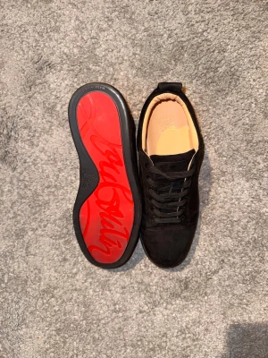 Svarta sneakers från Christian Louboutin - ‼️FAKE‼️Snygga svarta sneakers i mocka från Christian Louboutin med klassisk röd sula och svart snörning. Låg modell 