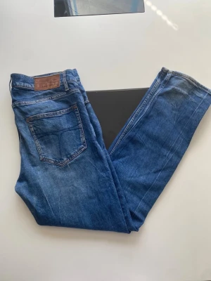 Blå jeans från Tiger of sweden  - Snygga blå jeans från 7 For All Mankind med klassisk femficksdesign och raka ben. Jeansen har en läderpatch bak i midjan och är gjorda i ett mjukt denimtyg. Perfekta till en avslappnad stil och funkar året runt.