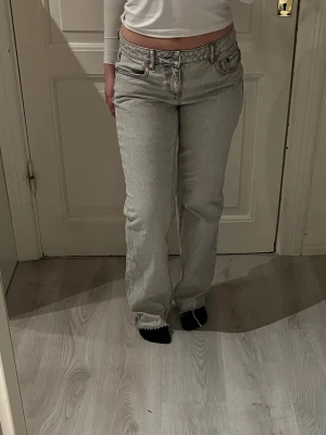 Ljusgrå raka jeans med hög midja - Säljer ett par ljusgrå jeans med raka ben och hög midja. Jeansen har fickor både fram och bak,  synliga sömmar. Materialet är denim i bomull. Dem är endast använda förtal gånger då dem är för små 
