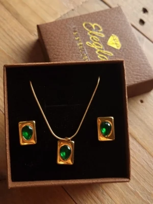 The Emerald Shine Smyckeset  - Lyft din stil med detta klassiska smyckesset i retrostil som ger en sofistikerad "old money"-estetik. Material: Rostfritt Stål ( S.Steel stämplat) Nickeltestat & allergivänlig                                        Ursprung : Thailand                               Storlek : Örhängen 1 cm bredd 1,3 cm långt      Halsband 21-23.5cm långt (justerbar)            -Inga prisförslag, tack.                      -Levereras i ett smyckeskrin som på bilden.  -Varan packas noggrant och säkert. 