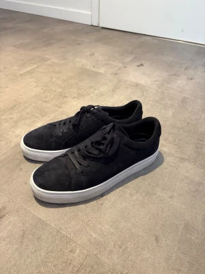 Nya Vagabond Paul 2.0 strl 43 - Stilrena svarta sneakers från Vagabond i mocka med klassisk låg profil och vita sulor. Skorna har svarta skosnören och en enkel, clean design som passar till det mesta. Perfekta för dig som gillar minimalistisk stil och vill ha ett par bekväma sneakers.                                                             Alldeles nya och använda ca 4ggr. Inköpta för lite mindre än ett år sedan och inte använt pga fel storlek. Hör av er vid eventuella funderingar!😃