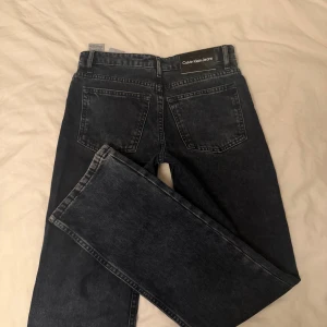 CALVIN KLEIN BLÅ HR STRAIGHT VISUAL BLUE BLACK - TJEJ - Snygga mörkblå jeans från Calvin Klein med klassisk femficksdesign och raka ben. Materialet är robust denim i bomull och passformen är normal. Säljer för att dem är för små. Har absolut inga skador och bara använda några gånger, dem är precis som nya och köpta från kidsbrandstore. 