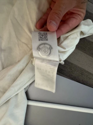 Vit t-shirt från Moncler - Säljer en klassisk vit t-shirt från Moncler. T-shirten har rund halsringning och är tillverkad i mjuk bomull för en skön känsla. Perfekt basplagg med diskret Moncler-logga i nacken. Enkel och stilren design som passar till allt.