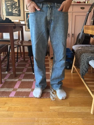 Blå raka jeans - Säljer ett par blå raka jeans med fransar längst ner vid bensluten. Jeansen har klassisk femficksmodell och normalhög midja. Materialet är denim i 100% bomull och färgen är ljusblå tvätt. Perfekta för en avslappnad och trendig look.