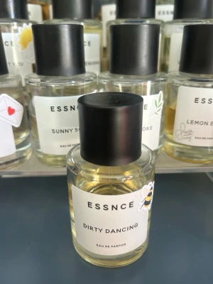 ESSNCE Dirty Dancing parfym - Parfymflaska från ESSNCE med doften Dirty Dancing. Flaskan är genomskinlig med svart rund kork och vit etikett. Innehållet är ljusgult och flaskan har en söt bi-sticker på sidan. Perfekt för dig som gillar unika dofter.