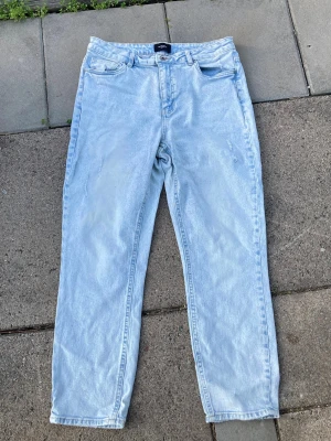 Snygga blåa mom jeans med hög midja - Säljer ett par snygga blåa mom jeans med hög midja och raka ben som har små slitningar(avsiktligt) på 3st ställen (Se bilder). Från Vero-Moda och är i storlek Medium. Säljes pga att dom inte används nåmer🤩☺️