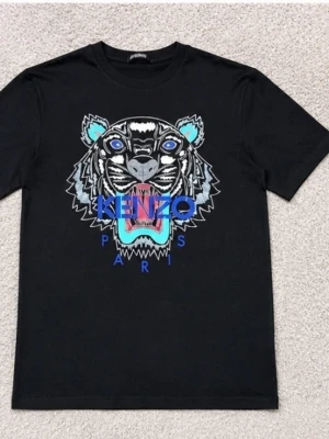 Svart Kenzo t-shirt med tigertryckk - Cool svart t-shirt från Kenzo med ikoniskt tigertryck och färgglada detaljer framtill. Klassisk passform och rund halsringning. Perfekt för dig som vill sticka ut med en statement-tee från ett välkänt märke.