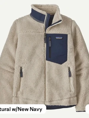 Beige Patagonia fleece - Säljer en supermjuk teddyjacka från Patagonia i beige med marinblå detaljer och bröstficka. Perfekt nu till sommaren, asmysig och står jättebra emot vind! Använd typ 3 gånger, inga tecken på använd. Köpte för 2500!
