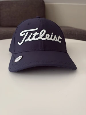Mörkblå Titleist keps - Mörklblå titleist golf keps med magnet i kepsen så man kan sätta markör på kepsen. Nytt skick 2 veckor gammal använd 5 rundor. Hör av er vid funderingar priset inte hugget i sten.